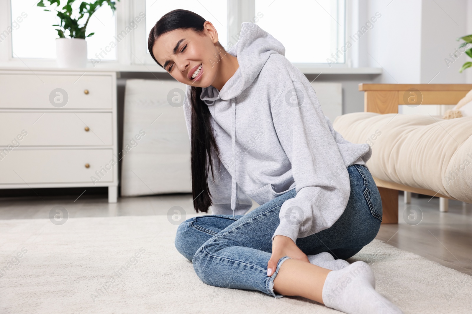 Photo of Woman suffering from leg pain on floor at home