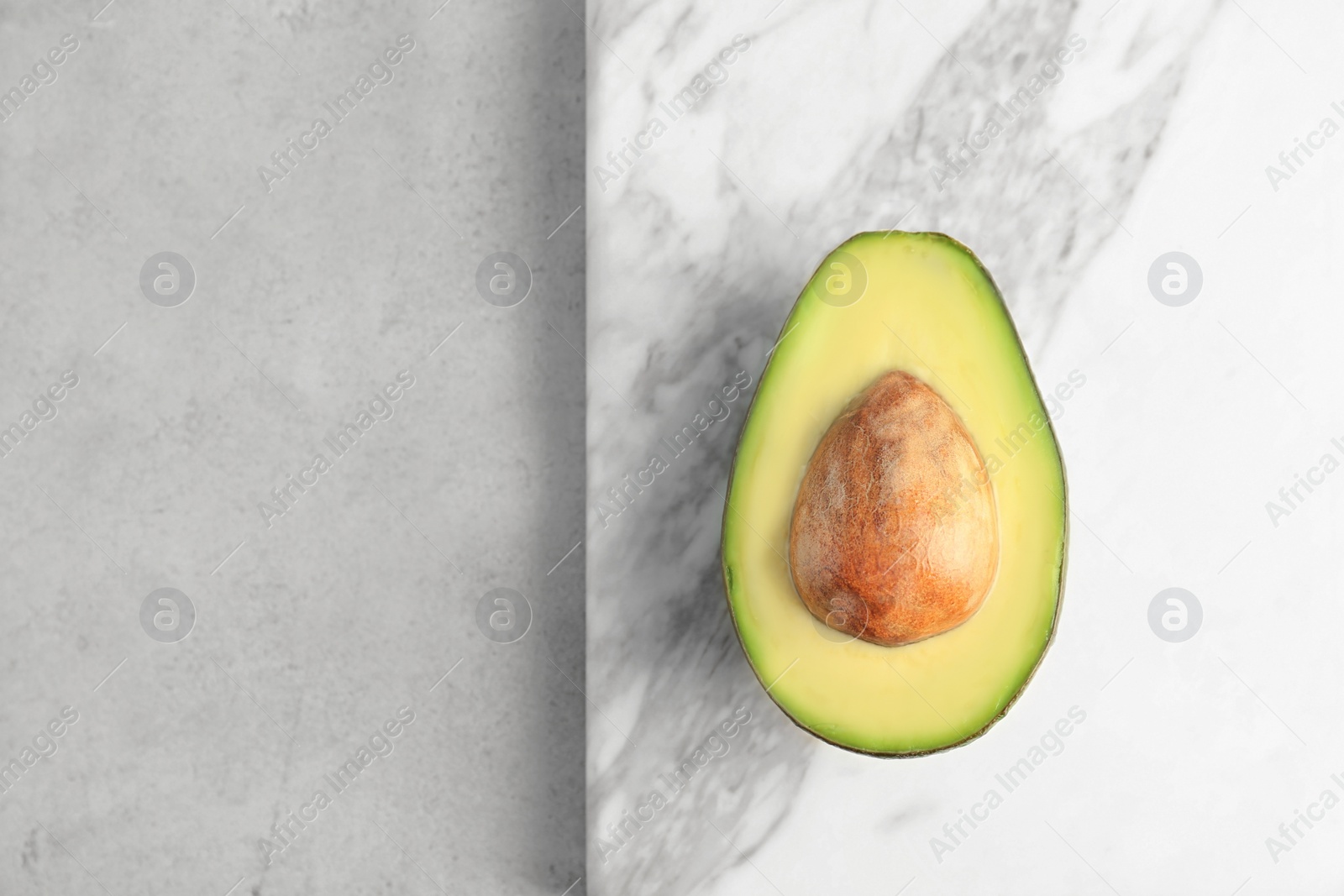 Photo of Stone board with cut avocado on light background, top view