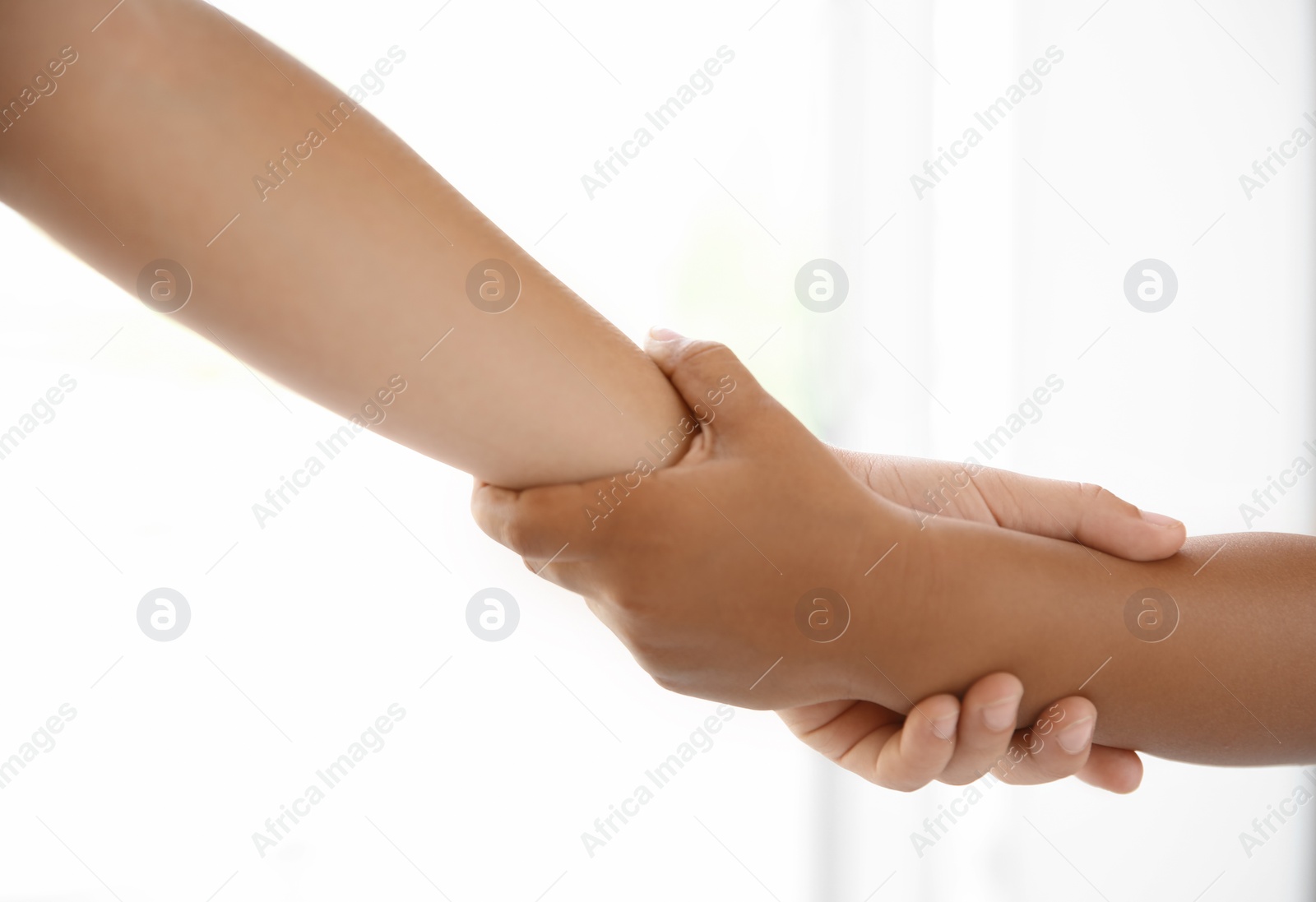 Photo of Children holding hands on light background, closeup. Unity concept