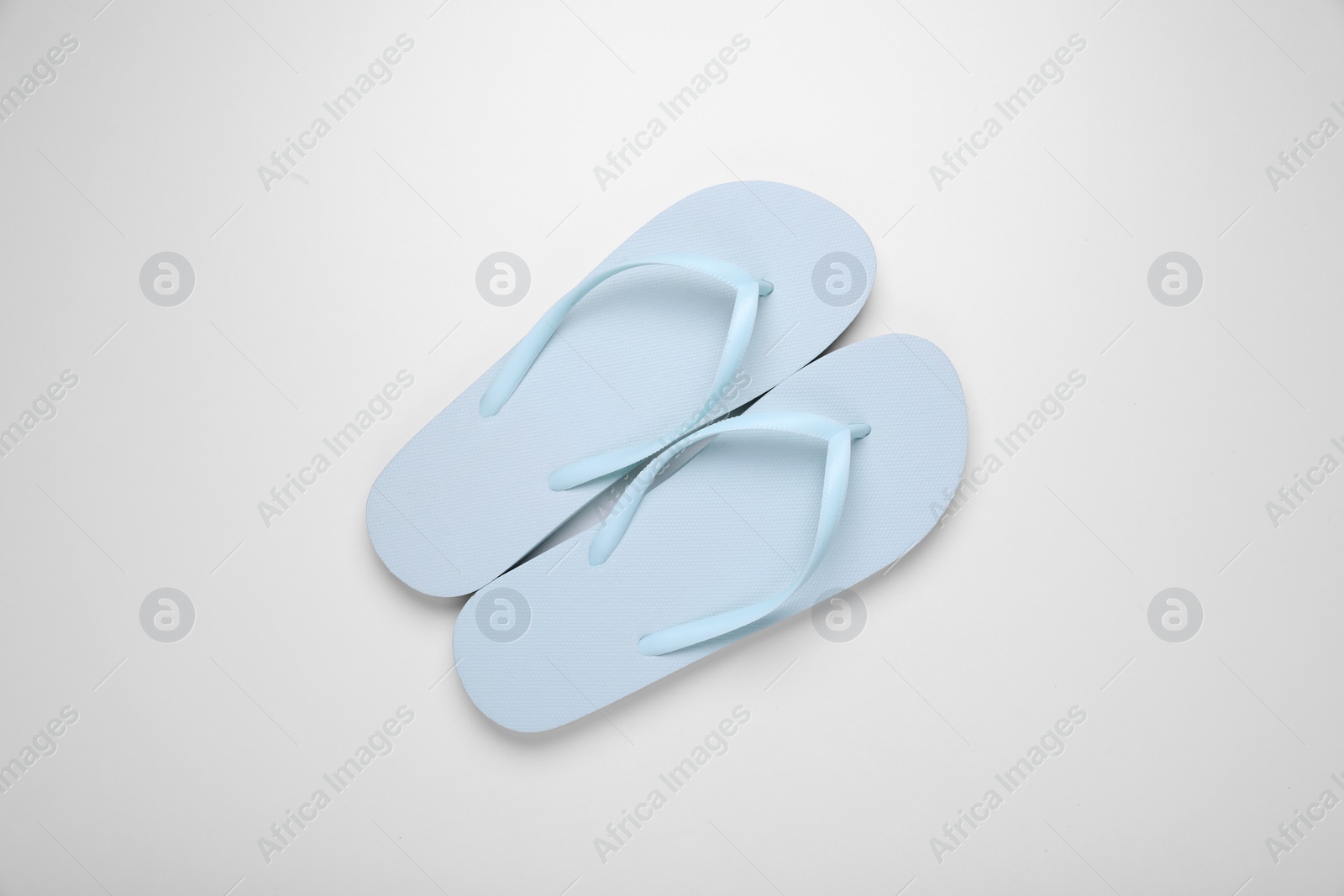 Photo of Light blue flip flops on white background, top view