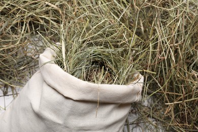 Burlap sack with dried hay on white wooden table, closeup