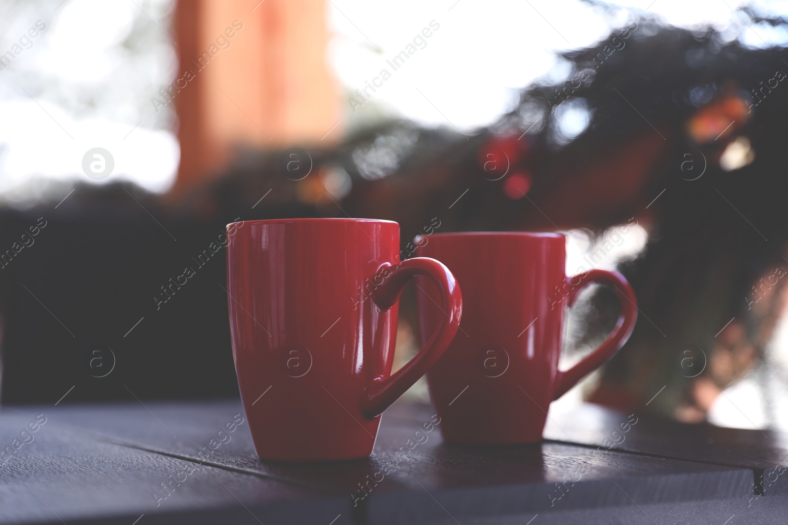 Photo of Red cups on wooden table outdoors. Winter vacation