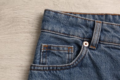 Photo of Stylish blue jeans on white wooden background, closeup of inset pocket