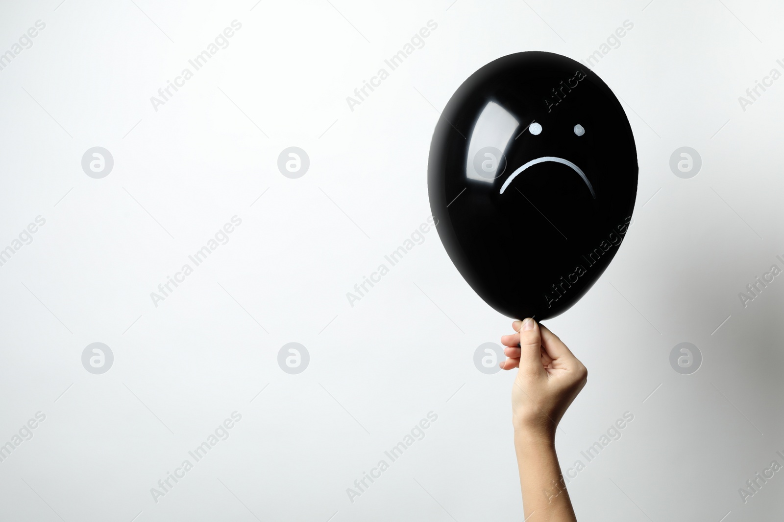 Photo of Woman holding balloon with sad face on white background, space for text. Threat of depression