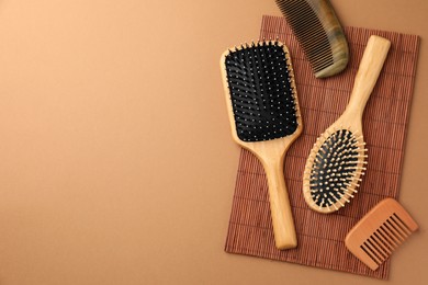 Photo of Wooden hairbrushes and combs on light brown background, flat lay. Space for text