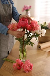 Photo of Florist making beautiful peony bouquet at table, closeup