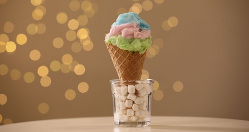 Sweet cotton candy in waffle cone on table against blurred lights