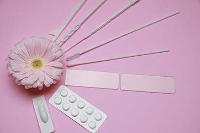 Gynecological treatment. Sterile tools, pills and gerbera flower on pink background, above view
