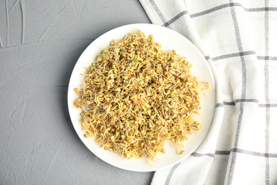 Plate with sprouted green buckwheat on light grey table, top view