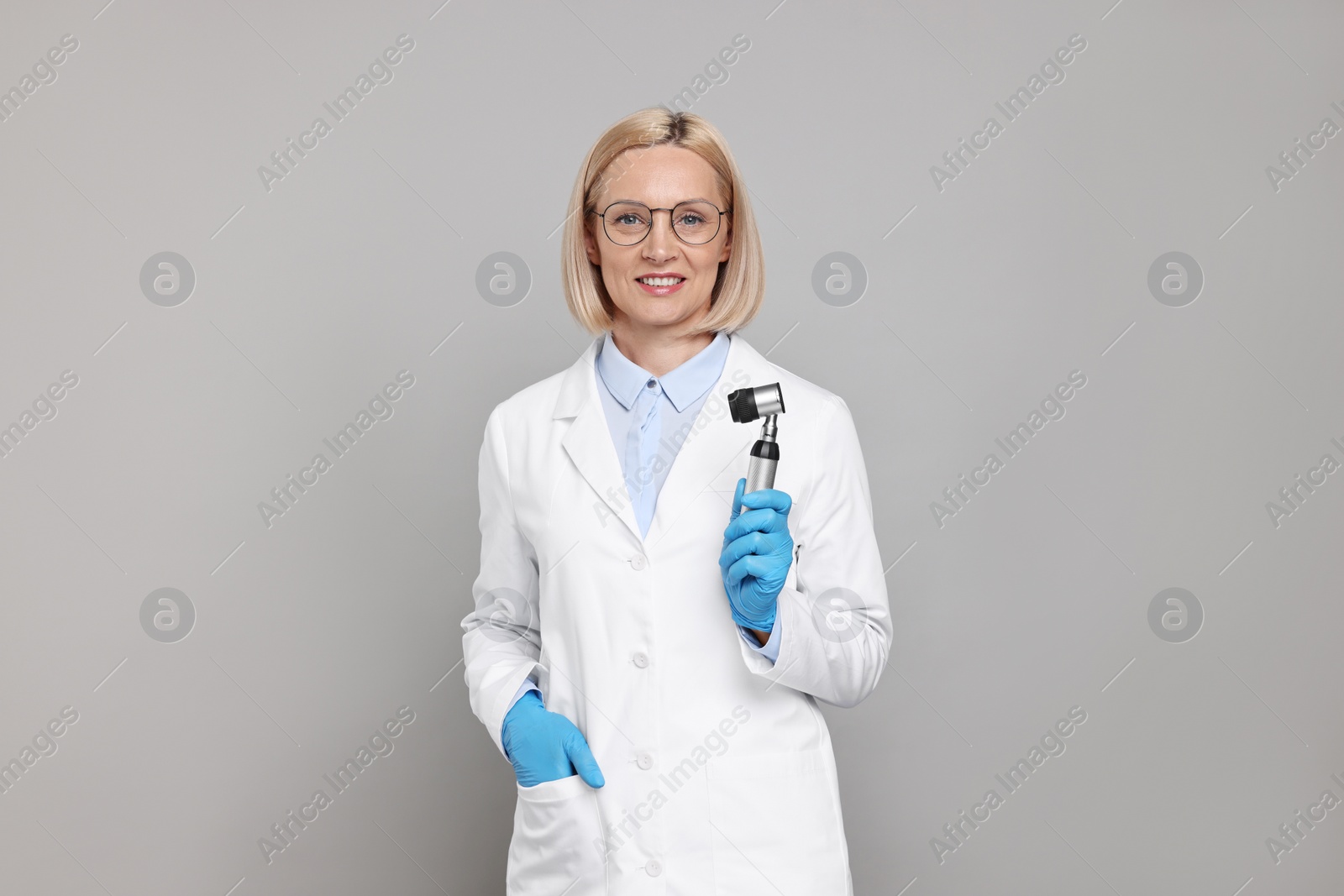 Photo of Happy dermatologist with dermatoscope on grey background