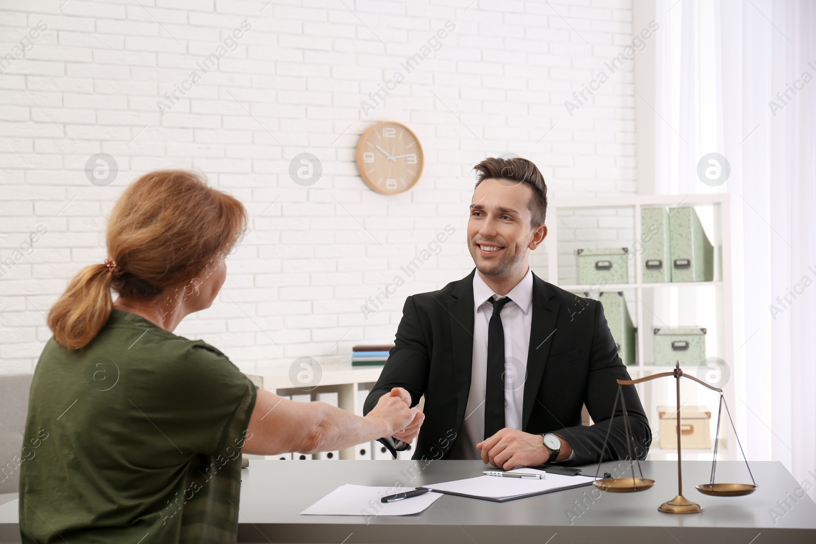 Photo of Young lawyer having meeting with senior client in office