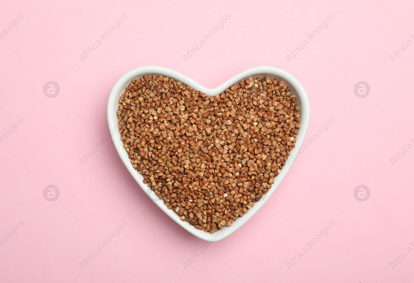 Photo of Buckwheat grains on pink background, top view