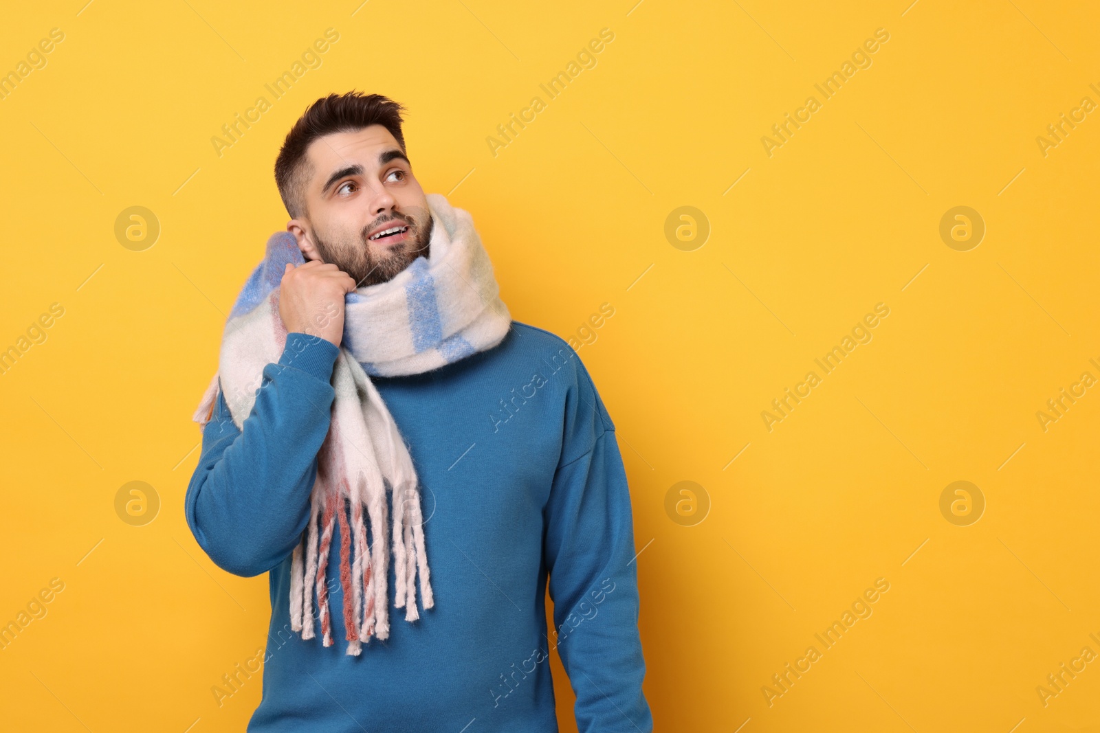 Photo of Smiling man in warm scarf on yellow background. Space for text
