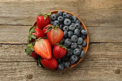 Photo of Fresh strawberries and blueberries on old wooden table, top view