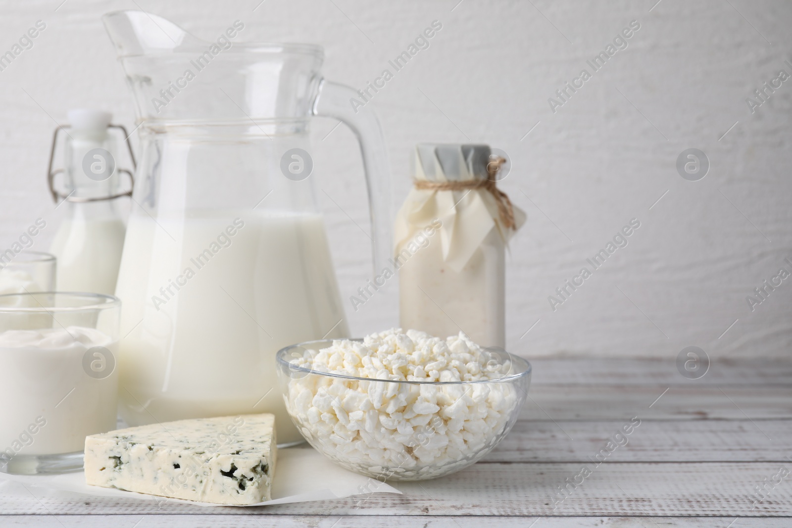 Photo of Different fresh dairy products on white wooden table. Space for text