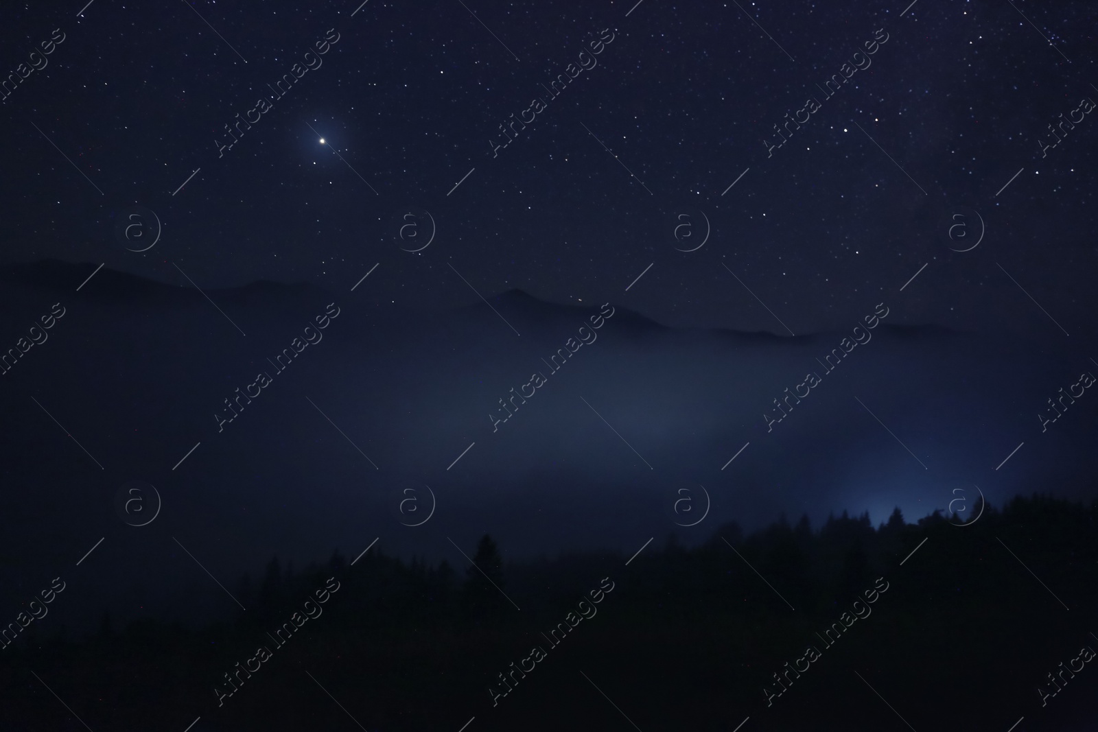 Photo of Picturesque view of night sky with beautiful stars over foggy hill