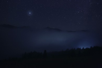 Photo of Picturesque view of night sky with beautiful stars over foggy hill