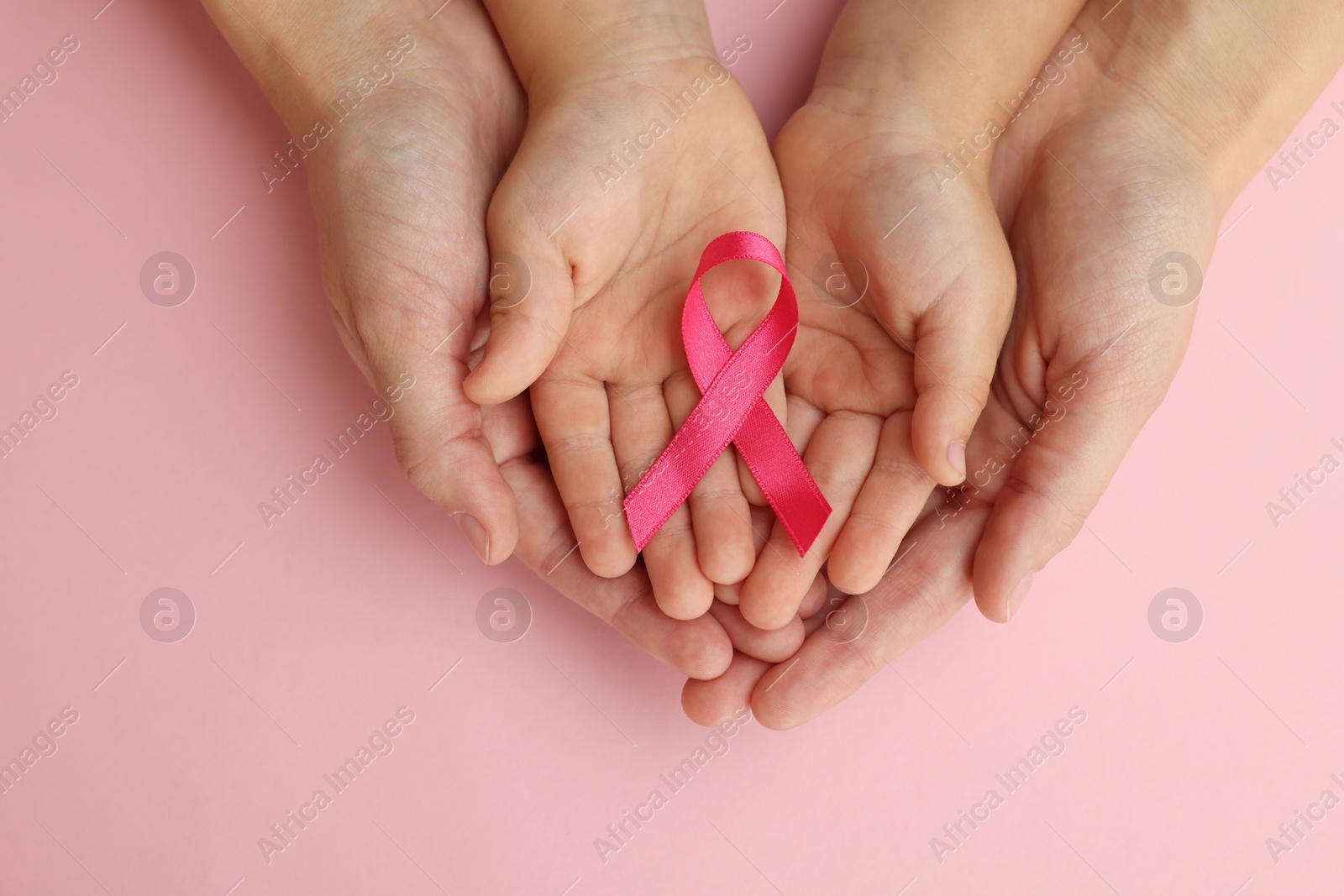 Photo of Woman and child holding pink ribbon on color background, top view. Breast cancer awareness