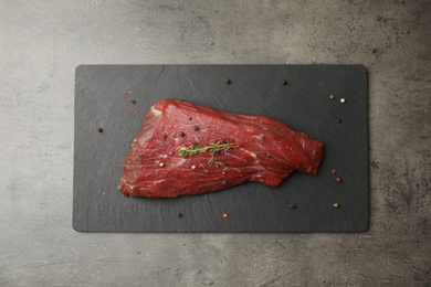Photo of Fresh raw beef cut with thyme and peppers mix on grey table, top view