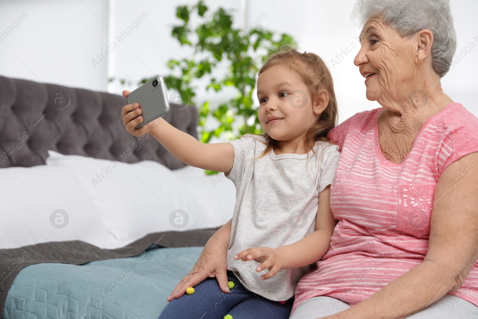 Photo of Cute girl and her grandmother taking selfie  at home