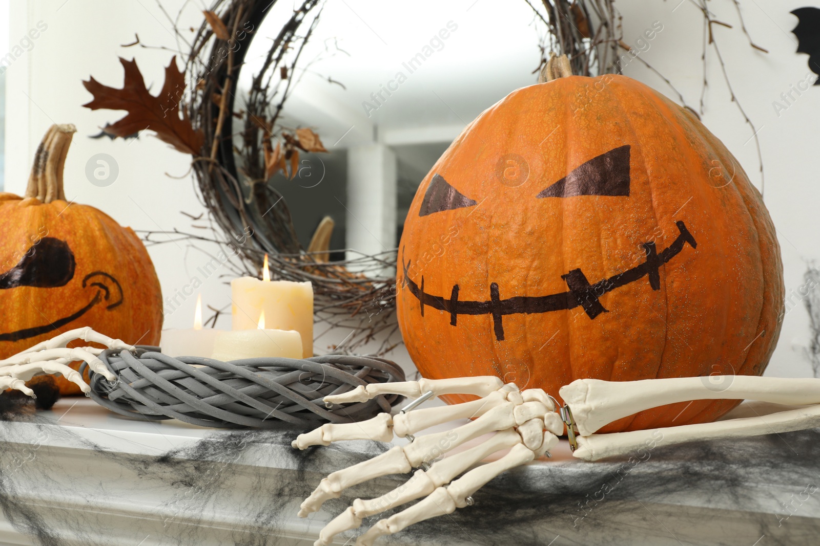 Photo of Pumpkins with drawn spooky faces and burning candles on table. Halloween decor