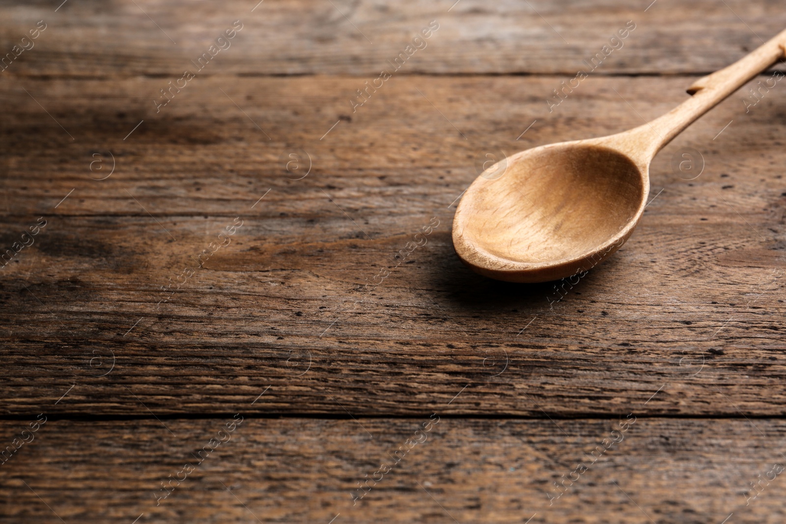 Photo of Clean empty spoon on wooden background, space for text