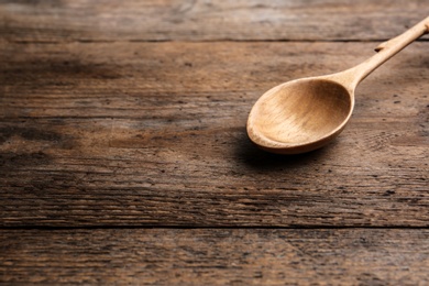 Clean empty spoon on wooden background, space for text