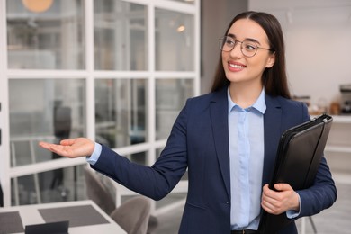 Happy real estate agent with leather portfolio in office