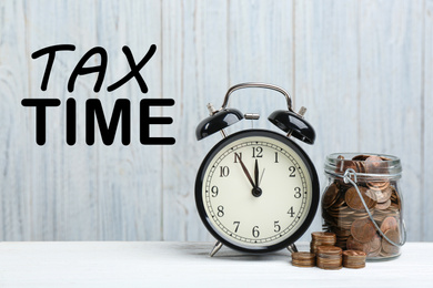 Time to pay taxes. Alarm clock, glass jar and coins on white table 