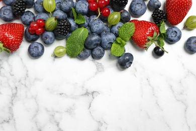 Mix of fresh berries on white marble table, flat lay. Space for text