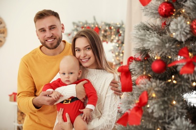 Photo of Happy family with cute baby near decorated Christmas tree at home