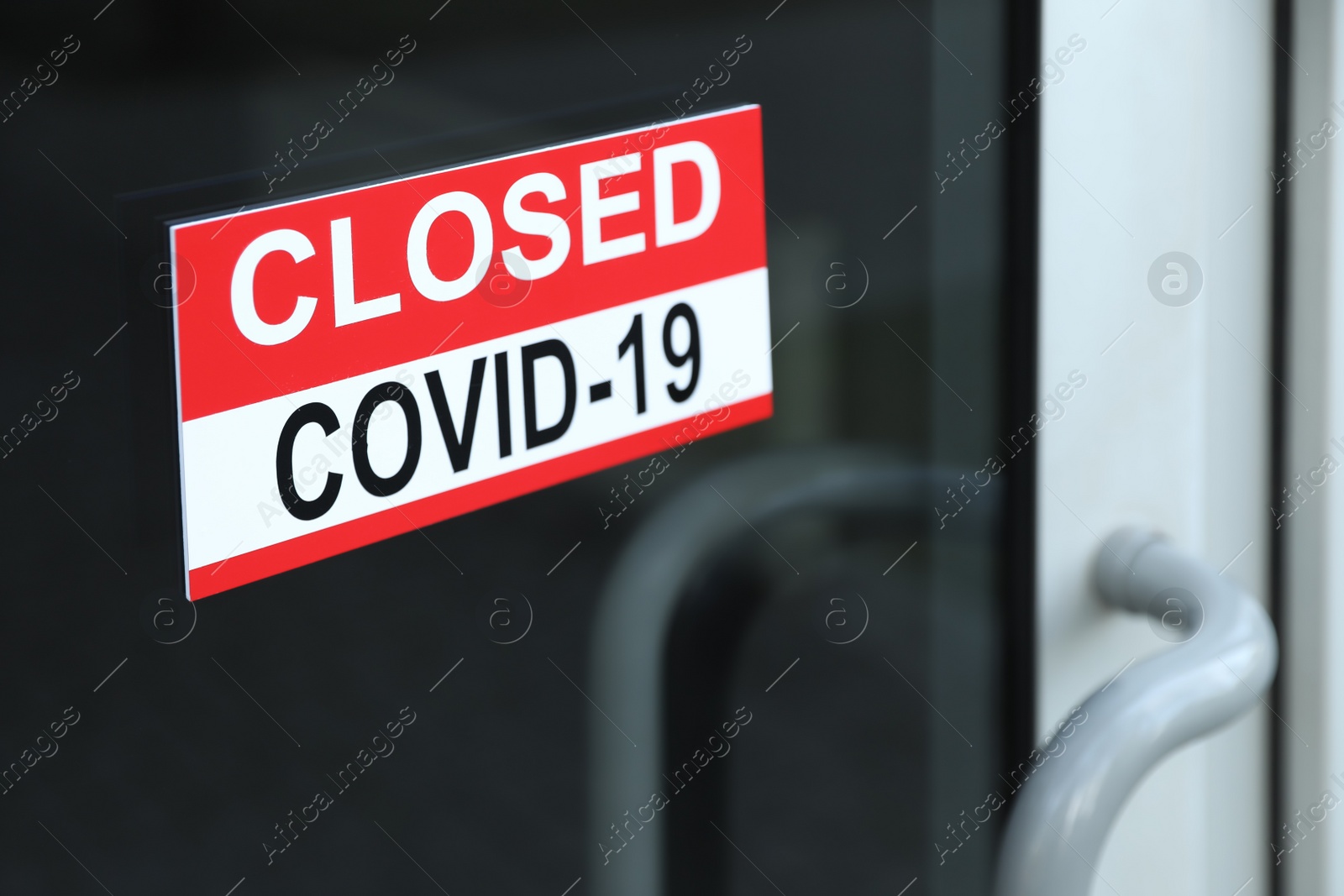 Photo of Red sign with words "Closed Covid-19" hanging on glass door