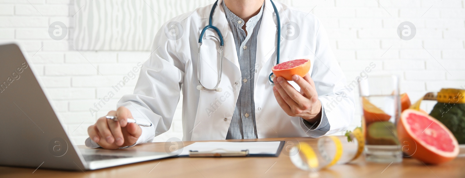 Image of Nutritionist working with laptop at desk in office. Banner design