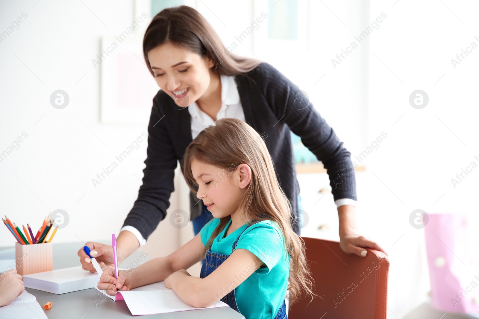 Photo of Female teacher helping girl with her task in classroom at school