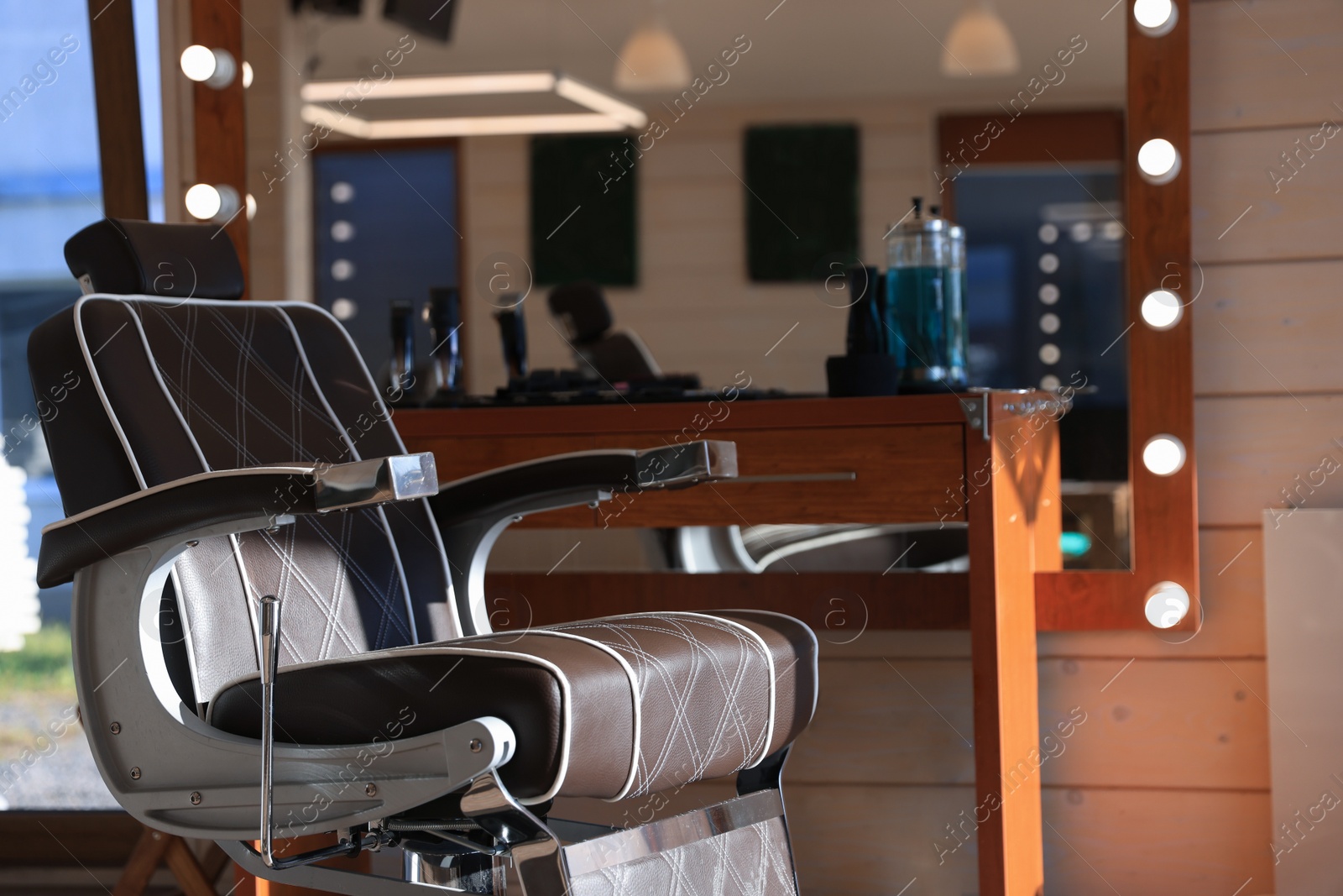 Photo of Stylish hairdresser's workplace with professional armchair and beautiful big mirror in barbershop