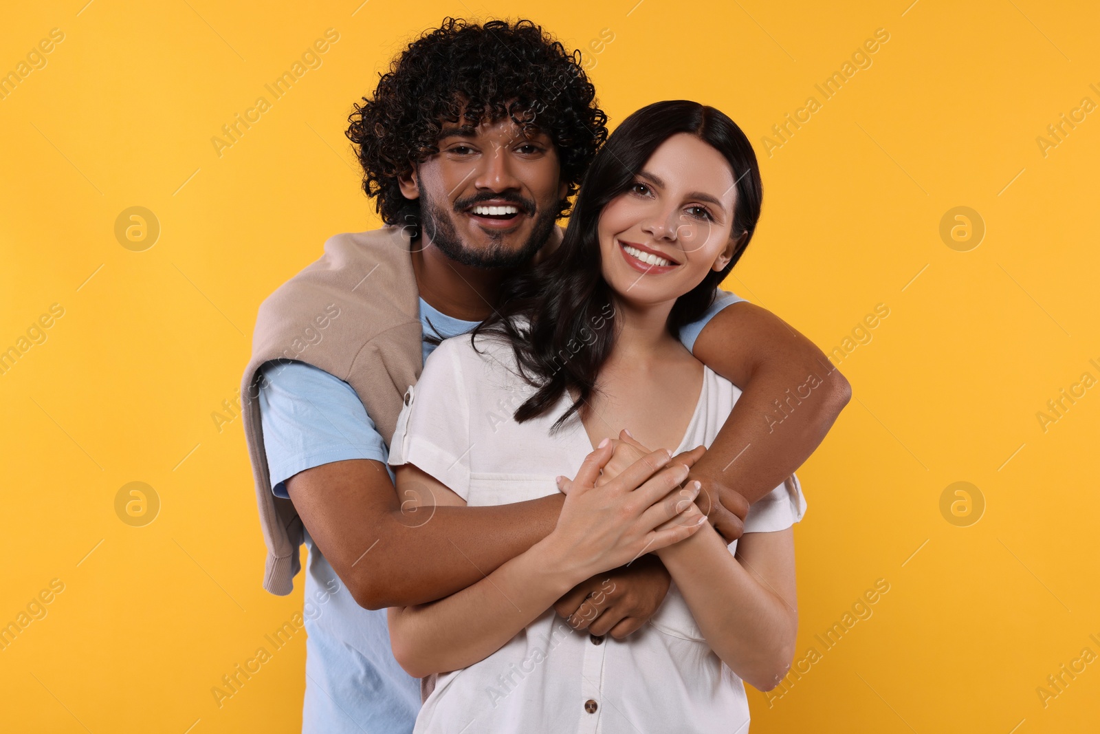 Photo of International dating. Happy couple hugging on yellow background