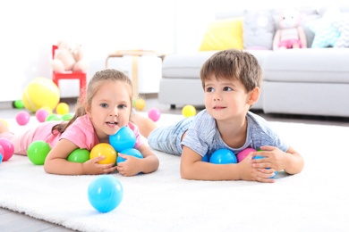 Photo of Cute little children playing with toys on floor at home
