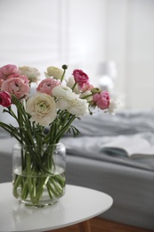 Photo of Bouquet of beautiful ranunculuses on table in bedroom
