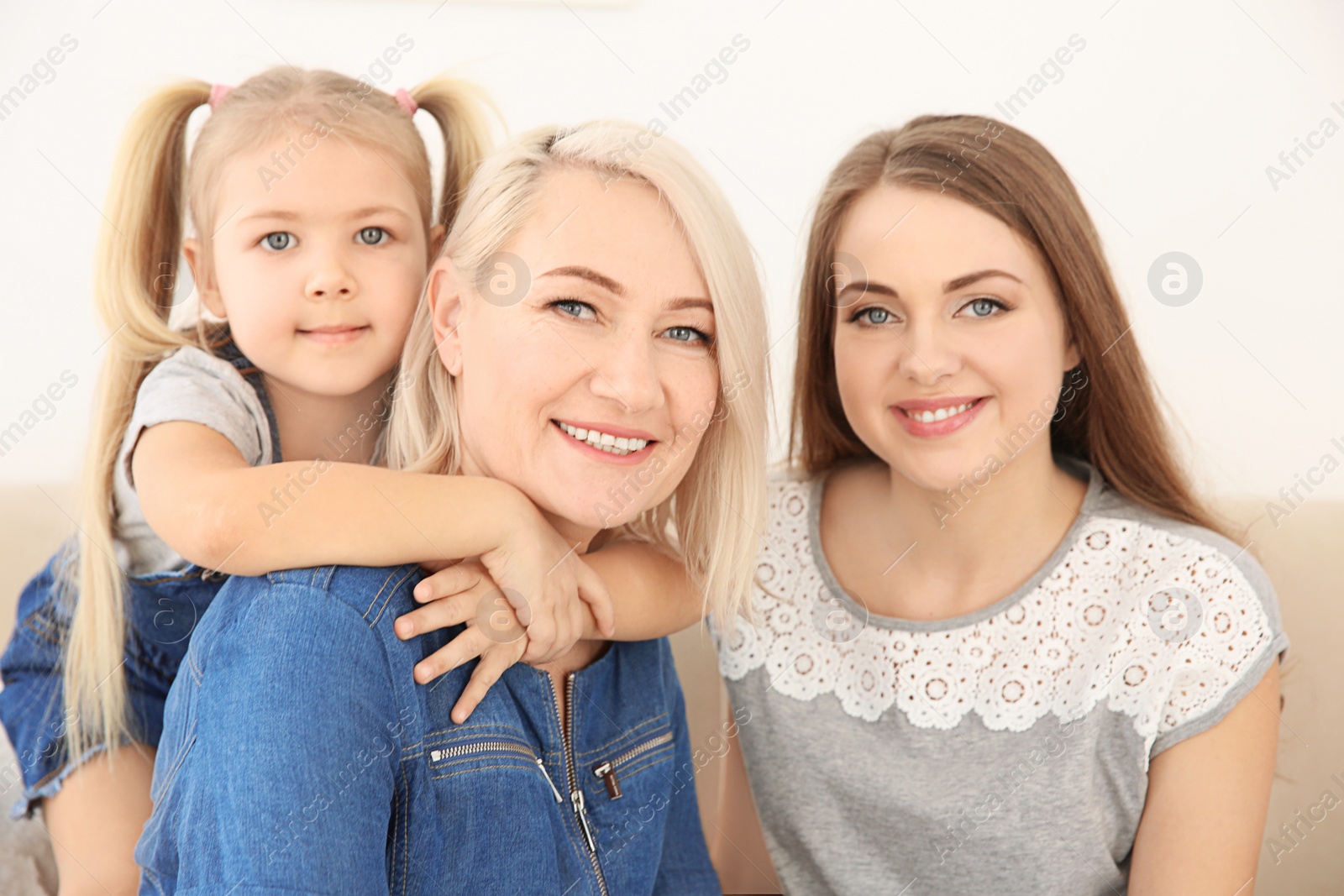 Photo of Happy young woman with her mother and daughter at home