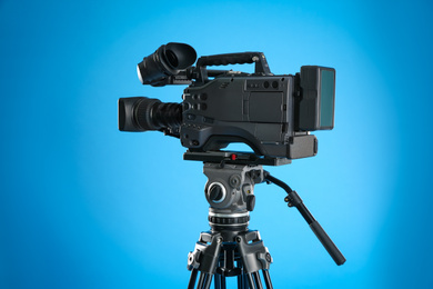 Photo of Modern professional video camera on blue background