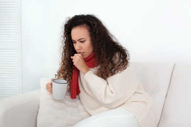 Sick African American woman with cup of hot drink at home
