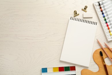 Photo of Flat lay composition with blank sketchbook on white wooden table. Space for text