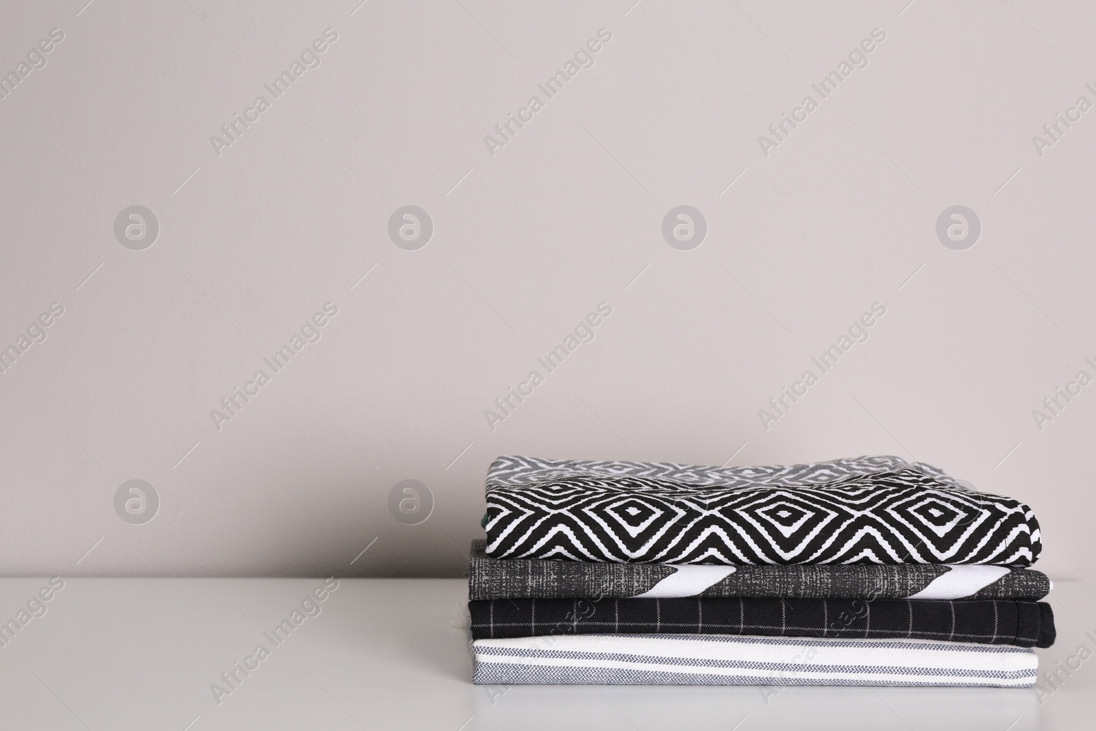 Photo of Stack of soft kitchen towels on white countertop near wall, space for text