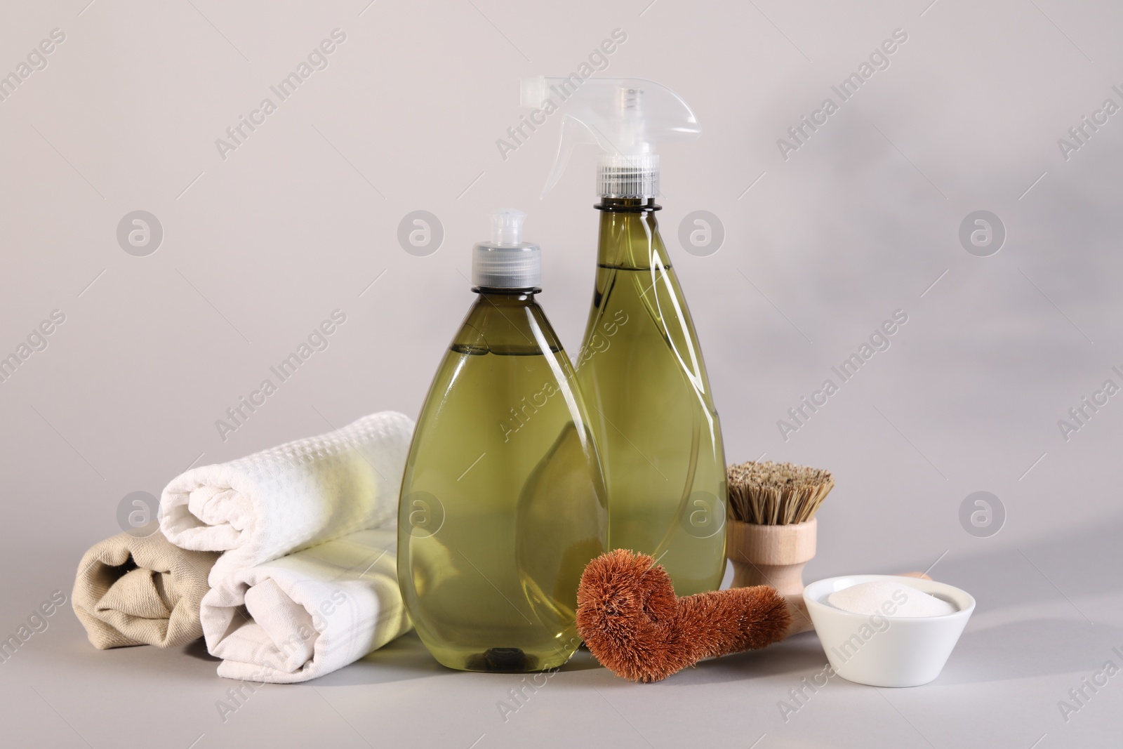 Photo of Bottles of cleaning product, brushes, rags and baking soda on light background