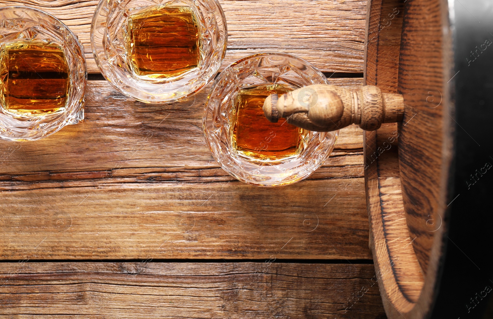 Photo of Glasses of whiskey and wooden barrel on table, flat lay. Space for text