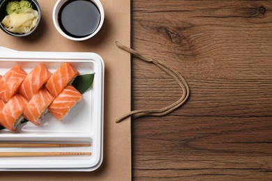 Photo of Food delivery. Delicious sushi rolls served on wooden table, flat lay with space for text