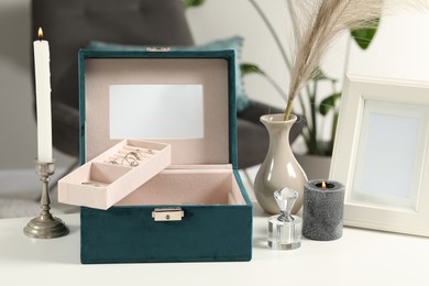 Photo of Jewelry box with many different accessories, perfume and decor on white table indoors