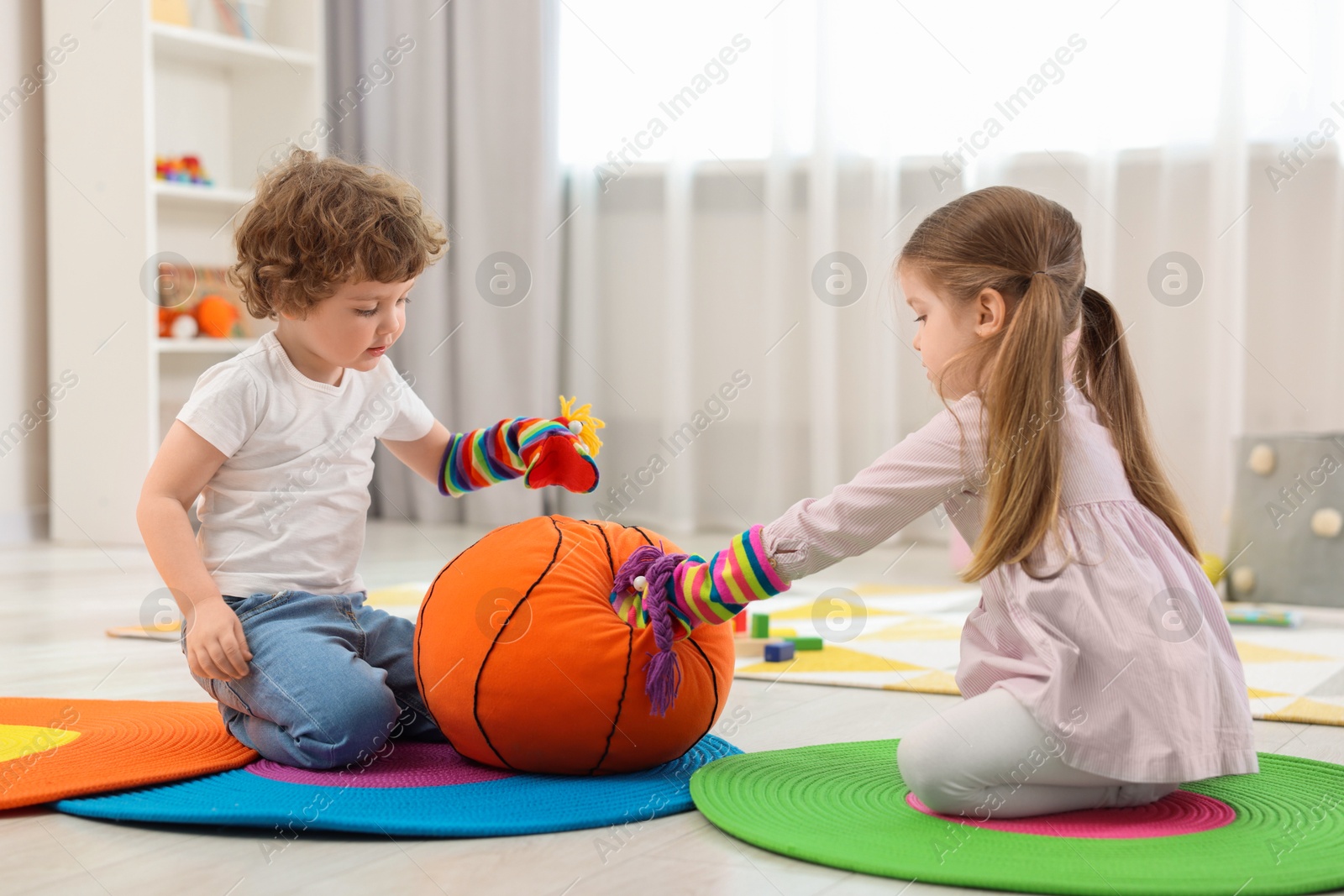 Photo of Cute little children playing with funny sock puppets and soft toy ball in kindergarten