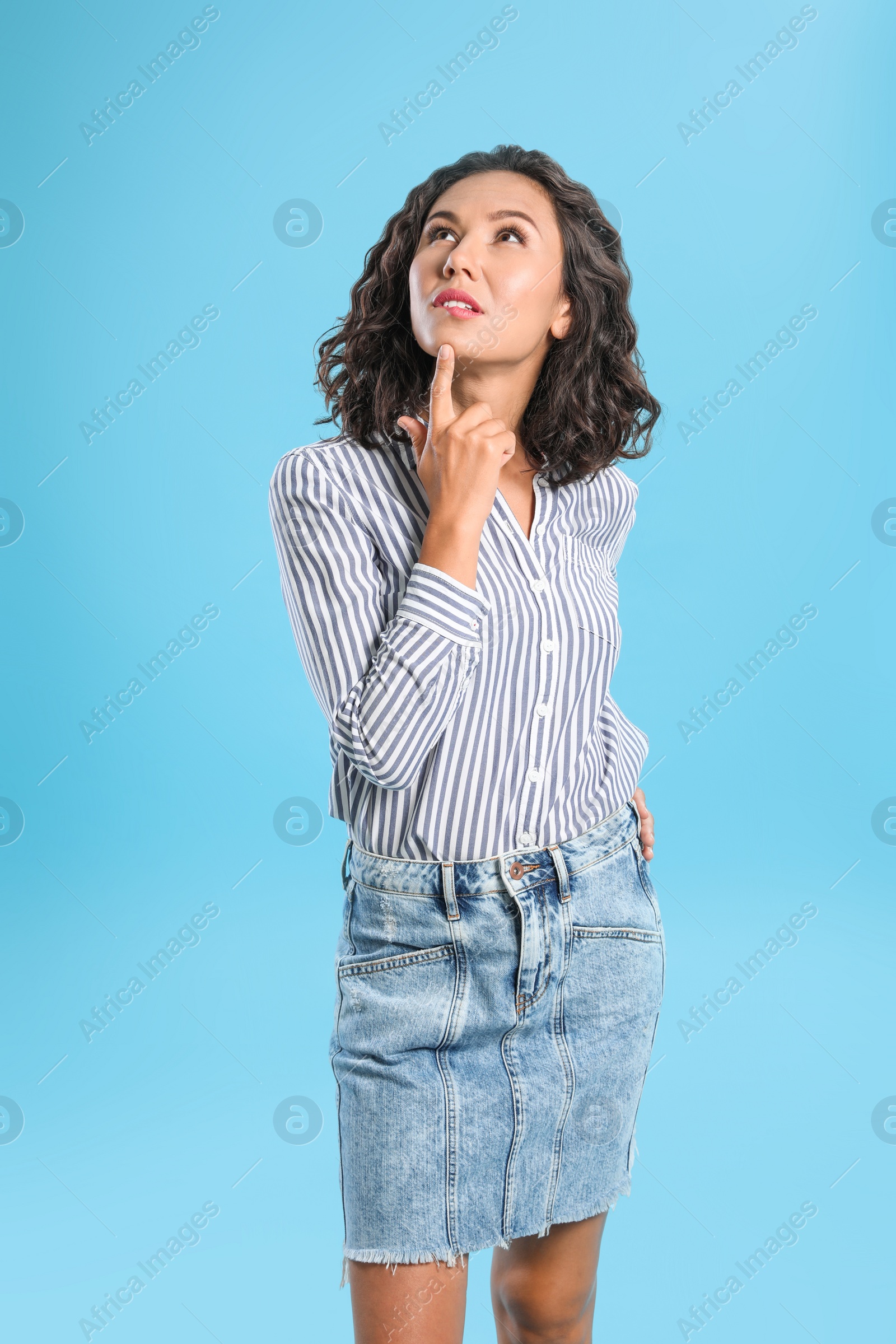 Photo of Thoughtful young woman in casual outfit on blue background