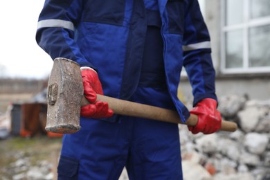 Man in uniform with sledgehammer outdoors, closeup